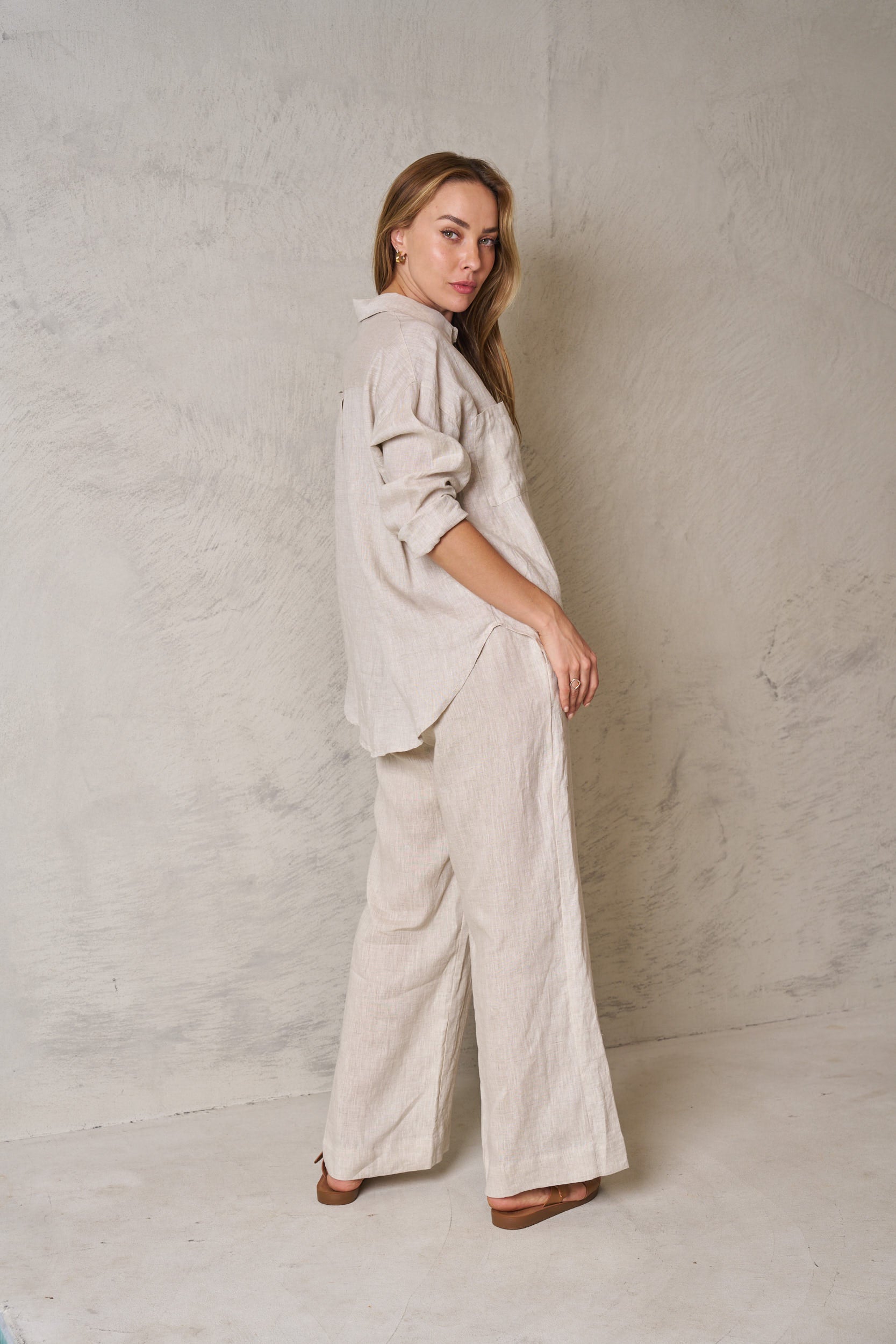 Woman wearing a beige outfit against a plain wall